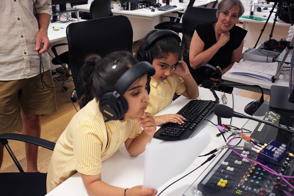 An action shot during this year's kids voice over workshop. Two girls work at the sound engineer's desk.