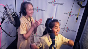 Action shot of two girls in the booth, enjoying the child voice over workshop.